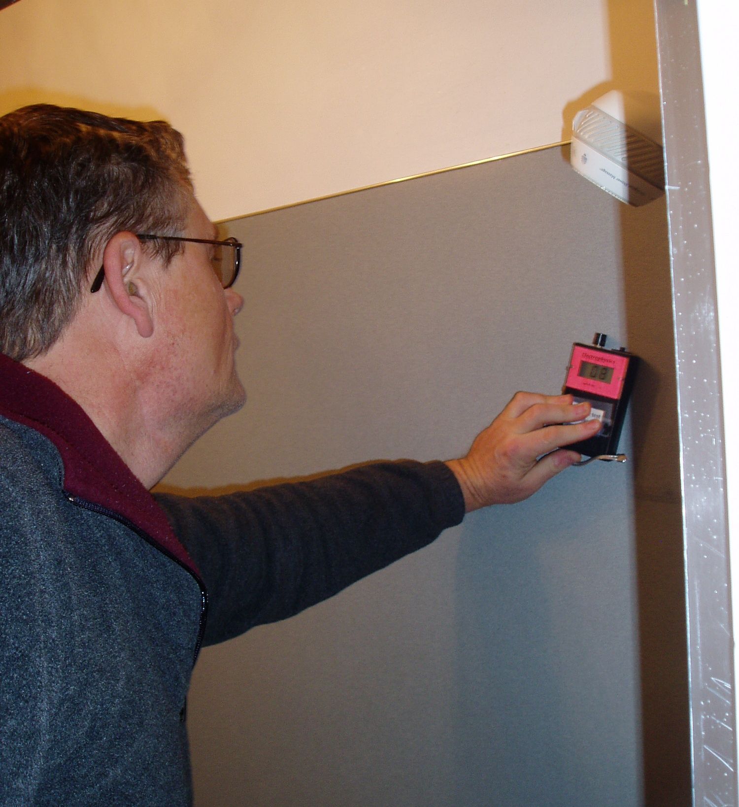 Steven Smith uses a moisture meter in a shower Photo