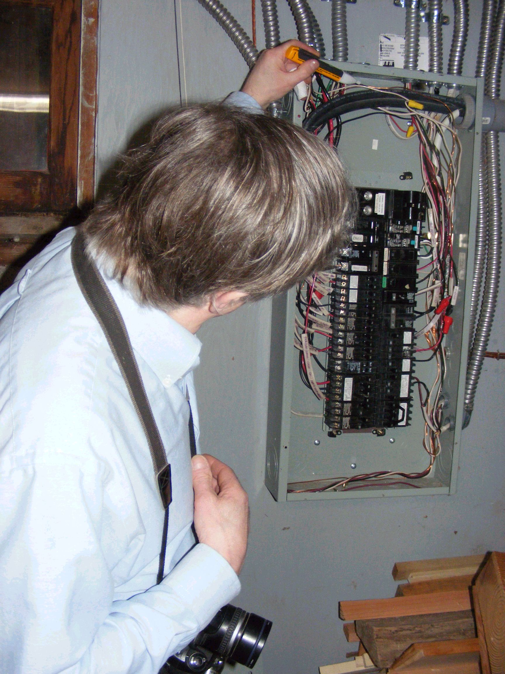 Charles Buell inspects inside a main electric panel